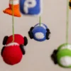 Close up of handmade crochet car nursery mobile showing individual miniature car detail and bright yarn stitch work