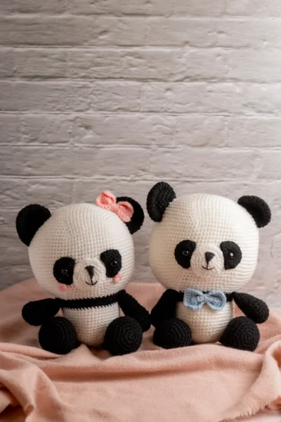 Full body view of crochet panda bear with blue and pink bow showing soft black and white yarn construction and friendly expression Melbourne