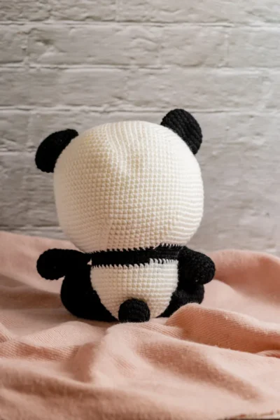 Full body view of crochet panda bear with blue bow showing soft black and white yarn construction and friendly expression Melbourne