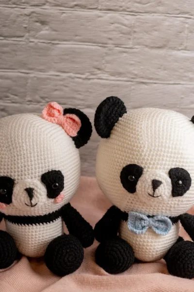 Full body view of crochet panda bear with blue and pink bow showing soft black and white yarn construction and friendly expression Melbourne