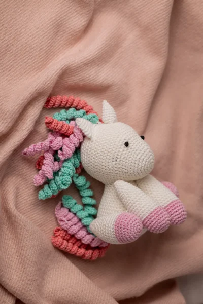 Handmade crochet amigurumi unicorn with soft white body and vibrant rainbow mane made by artisan crafters magical kids gift Australia