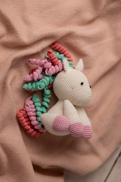 Handmade crochet amigurumi unicorn with soft white body and vibrant rainbow mane made by artisan crafters magical kids gift Australia