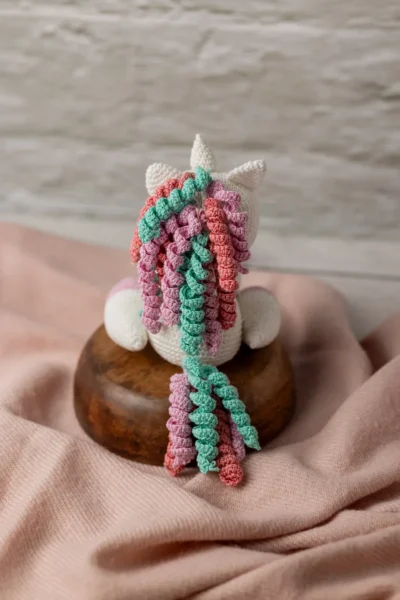 Handmade crochet amigurumi unicorn with soft white body and vibrant rainbow mane made by artisan crafters magical kids gift Australia