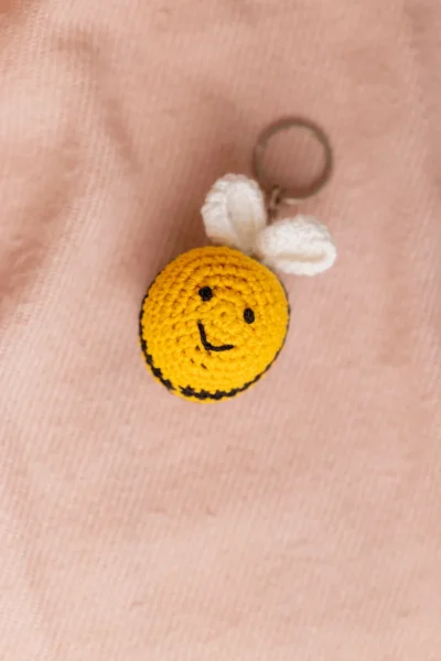 Close up of handmade honey bee crochet keyring showing yellow black stripe and wing stitch detail