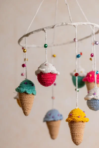 Crochet ice cream cupcake cot hanging showing full mobile with colourful sweet treat characters handmade ethical nursery decor