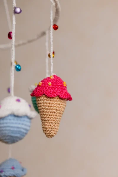 Crochet ice cream cupcake cot hanging showing full mobile with colourful sweet treat characters handmade ethical nursery decor