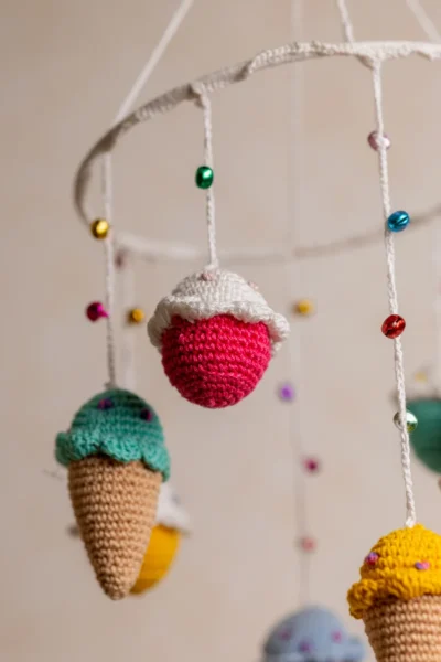 Crochet ice cream cupcake cot hanging showing full mobile with colourful sweet treat characters handmade ethical nursery decor