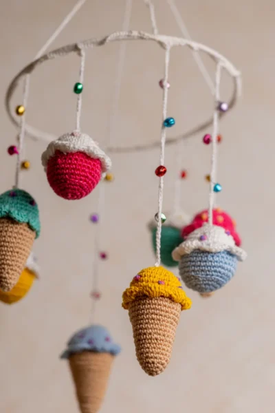 Crochet ice cream cupcake cot hanging showing full mobile with colourful sweet treat characters handmade ethical nursery decor