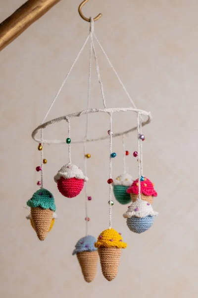 Crochet ice cream cupcake cot hanging showing full mobile with colourful sweet treat characters handmade ethical nursery decor