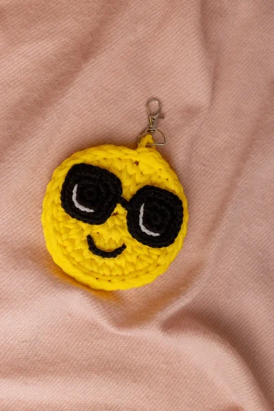 Yellow crochet smiley face keychain showing stitched eyes and smile handmade ethical bag charm Australia