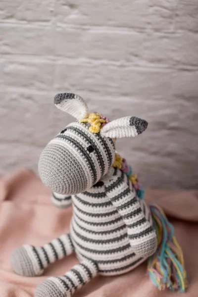 Full body view of crochet Zippy zebra showing black and white stripe pattern and bright multicolour rainbow mane Melbourne