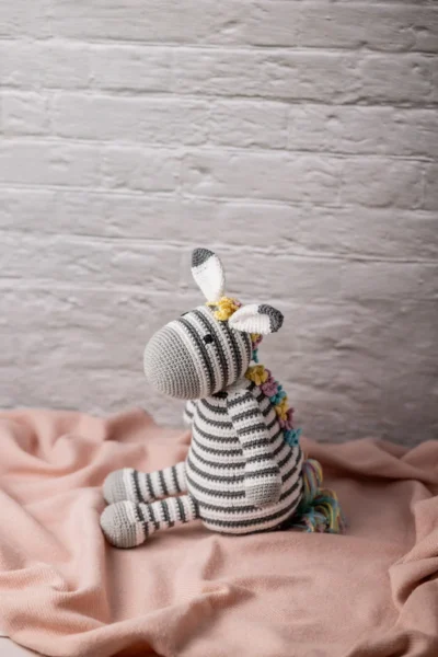 Full body view of crochet Zippy zebra showing black and white stripe pattern and bright multicolour rainbow mane Melbourne