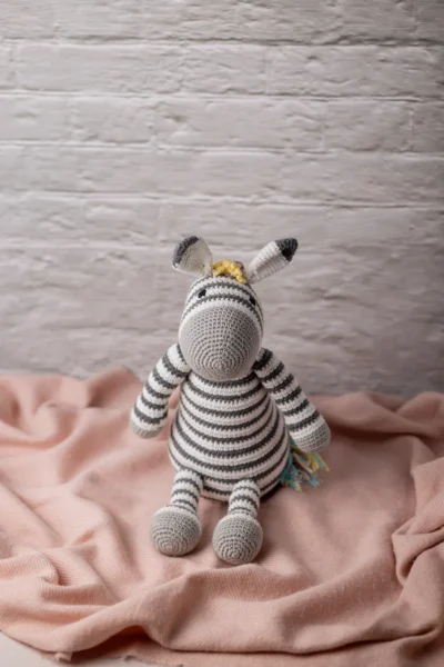 Handmade crochet Zippy the zebra with classic black and white stripes and vibrant rainbow mane made by artisan crafters kids gift Australia