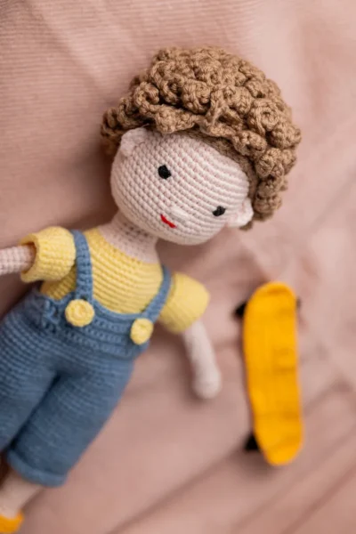 Amigurumi skater boy doll seated with miniature skateboard showing tight secure yarn stitching and detailed sneakers Australia