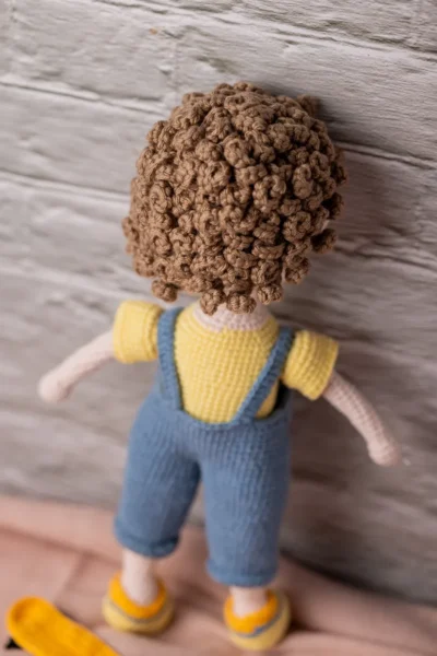 Amigurumi skater boy doll seated with miniature skateboard showing tight secure yarn stitching and detailed sneakers Australia