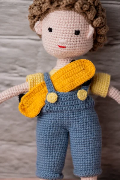 Close up of handmade crochet boy doll face showing hand stitched features and soft yarn texture artisan made soft toy Australia