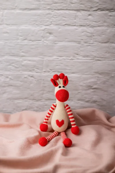 Azizi crochet giraffe shown seated on nursery shelf safari themed decor slim shape fits in pram bag shipped from Melbourne