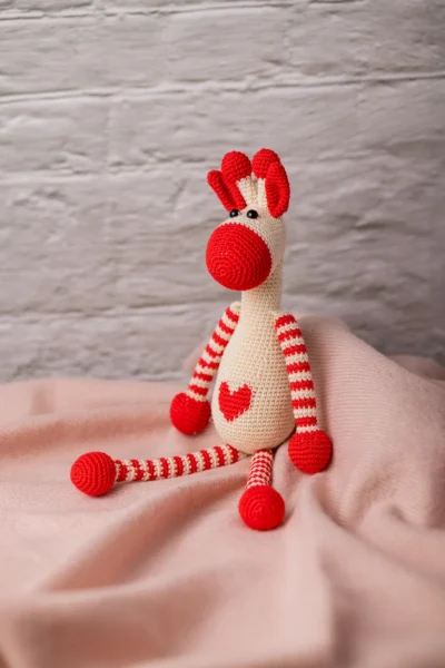 Azizi crochet giraffe shown seated on nursery shelf safari themed decor slim shape fits in pram bag shipped from Melbourne