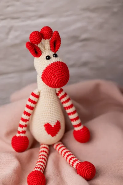 Azizi crochet giraffe shown seated on nursery shelf safari themed decor slim shape fits in pram bag shipped from Melbourne