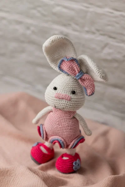 Full body view of crochet bunny rabbit doll in pink crocheted dress showing long ears soft yarn body and bow detail Melbourne