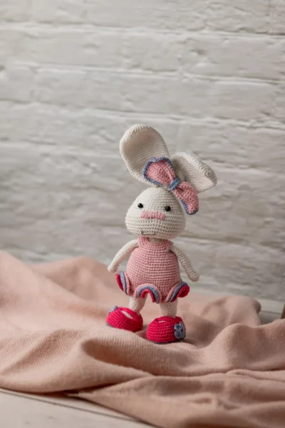 Full body view of crochet bunny rabbit doll in pink crocheted dress showing long ears soft yarn body and bow detail Melbourne