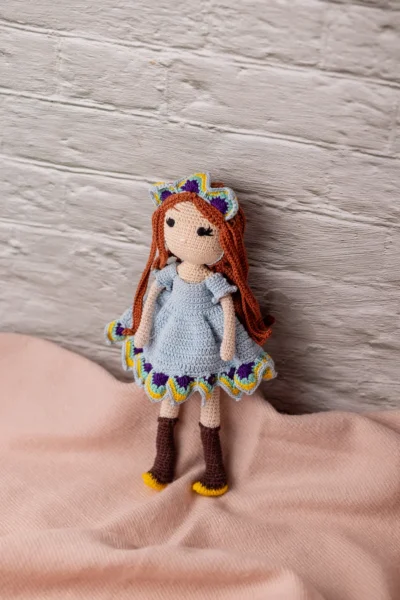 Full body view of crochet doll with red hair blue dress and boots showing soft yarn body and stitched face Melbourne Australia