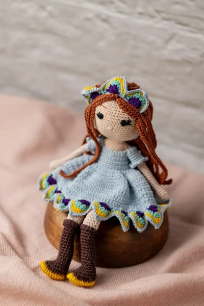 Full body view of crochet doll with red hair blue dress and boots showing soft yarn body and stitched face Melbourne Australia