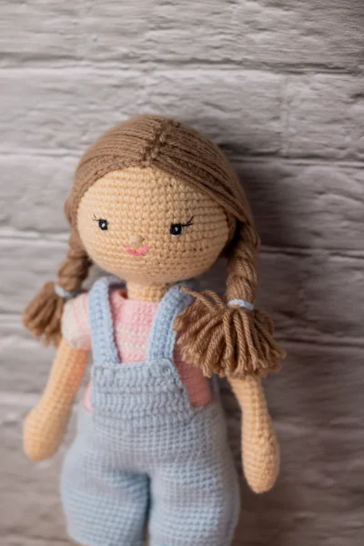 Full body view of crochet Ruby doll in classic blue dungarees showing soft amigurumi proportions and yarn texture Melbourne