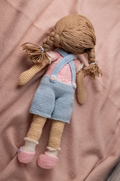 Full body view of crochet Ruby doll in classic blue dungarees showing soft amigurumi proportions and yarn texture Melbourne
